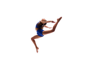 Pediatric aged girl jumping in the air with her legs split and head thrown back in a blue shirt and shorts that sparkle, in Jacksonville, FL