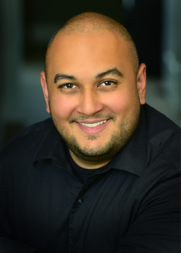 Man smiling at camera in black shirt, with a little facial hair